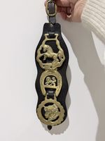 Vintage brass horse medallions mounted on a traditional leather martingale strap