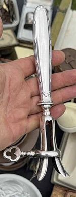 A silver-plated ham shank holder With pronged Screw securing mechanism.