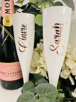 White Champagne Flutes with rose gold writing.