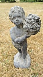 19th Century lead garden statue of a cherub boy presenting a bouquet of flowers