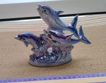 Opalescent ceramic ornament featuring three blue dolphins on sea waves