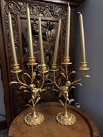 A Pair of Vintage Gilt Brass Three Branch Cherub Adorned Candlestick Holders
