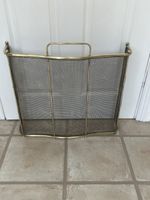 An antique brass fire guard screen