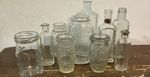 collection of assorted clear vintage glass bottles and jars.